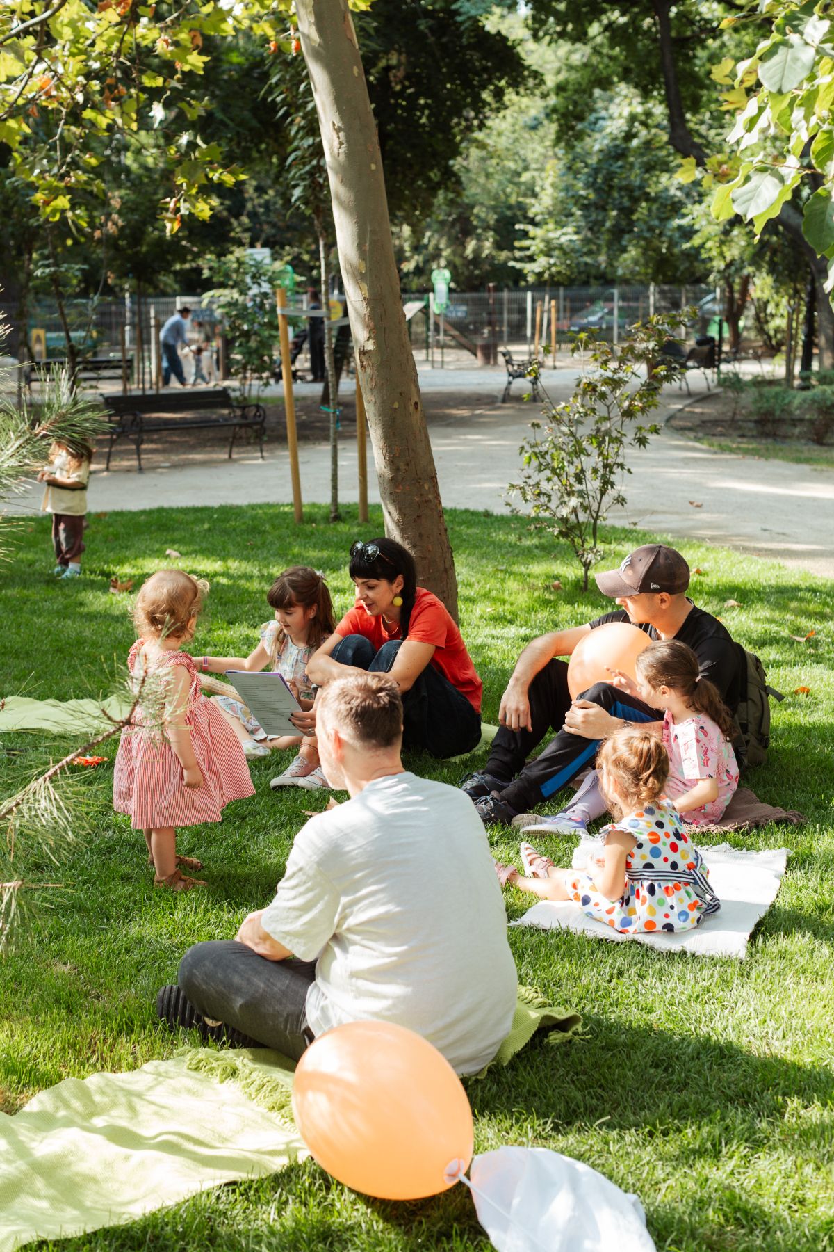 Părinți și copii pe pături în parc